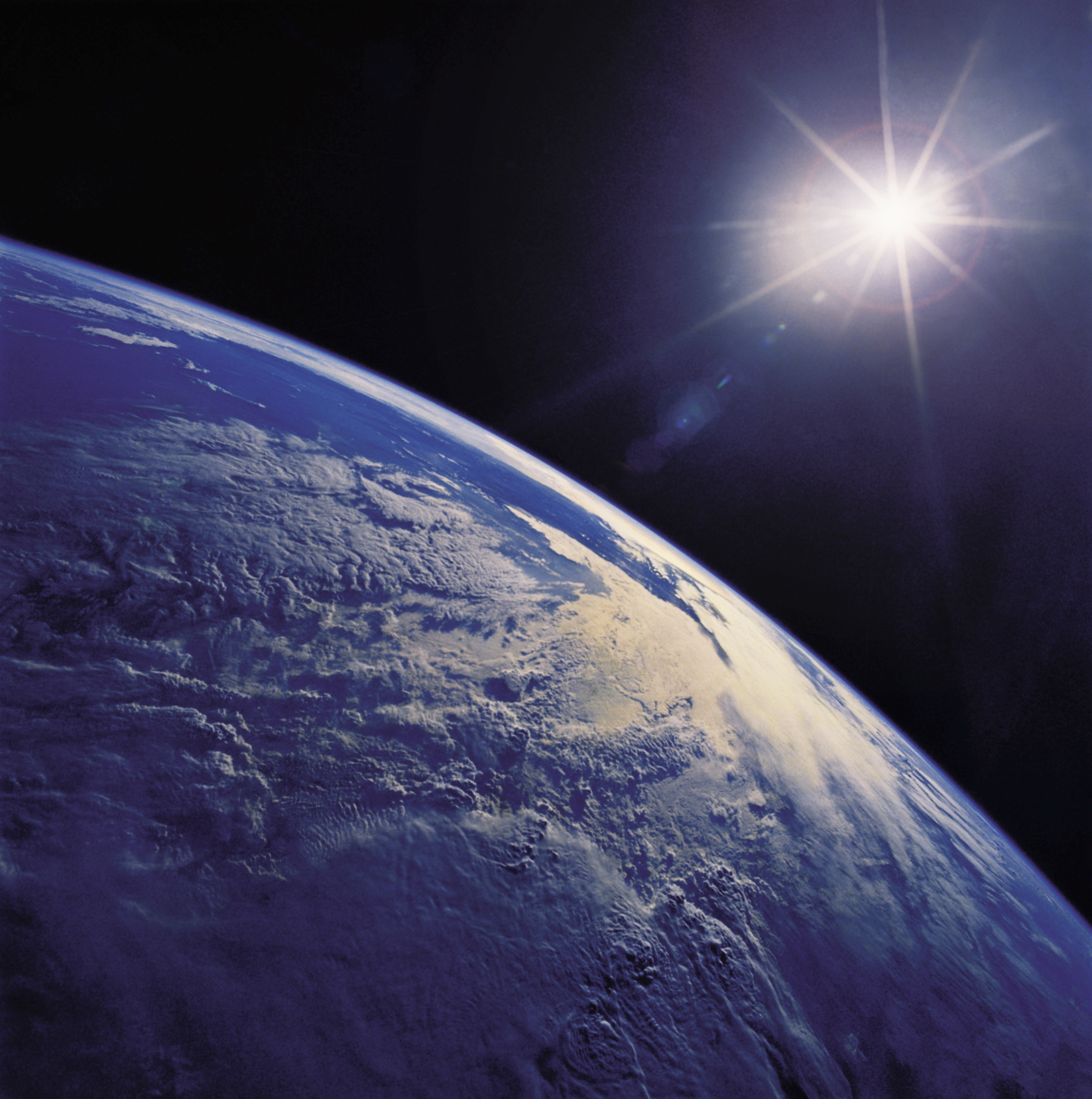 A breathtaking view of Earth from space reveals the planet's curvature and vibrant cloud formations, echoing the diverse life histories unfolding below. The sun shines brightly in the top right corner, casting light and creating a lens flare effect.
